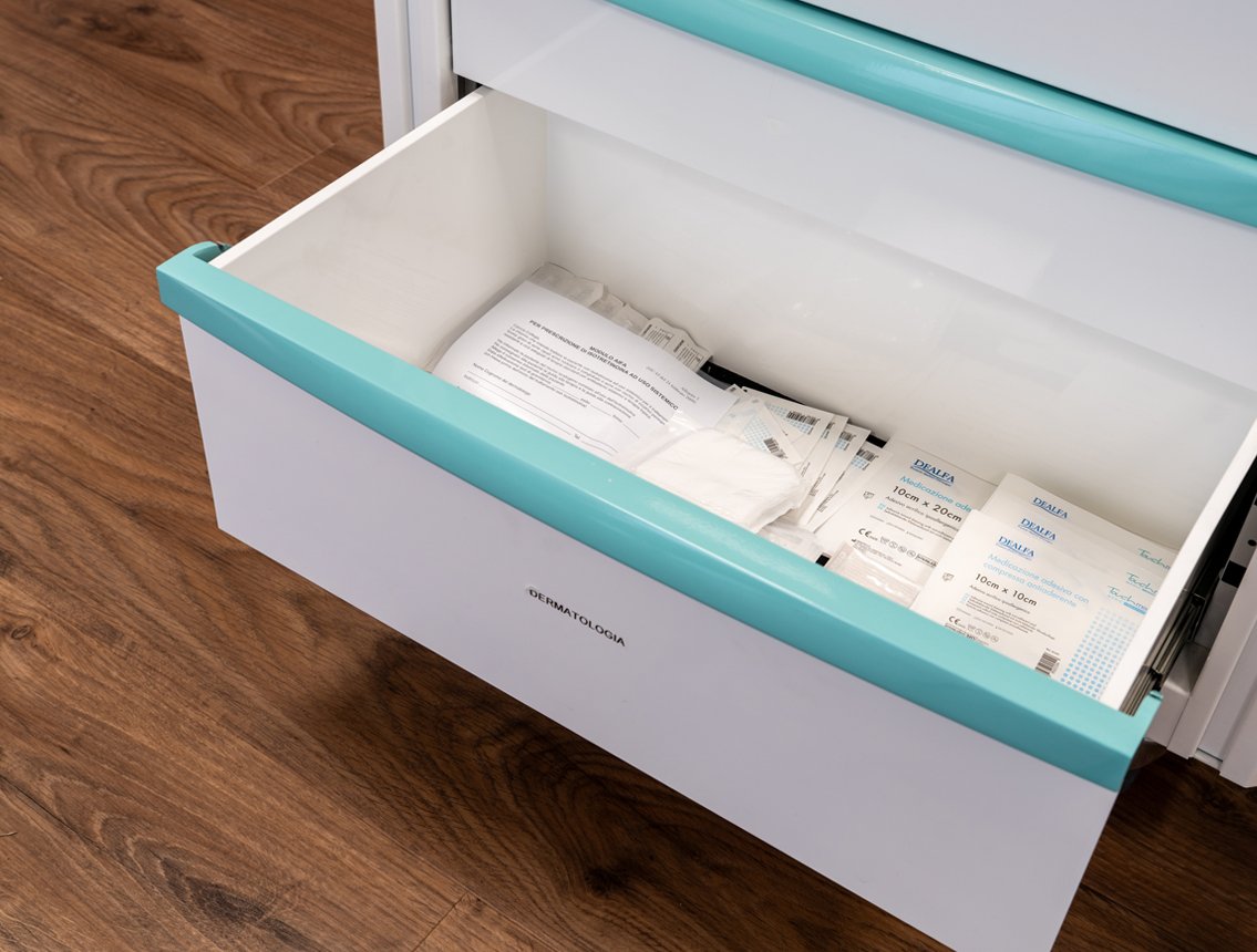 Mobili da officina 3D Cassetto aperto di Beta con forniture mediche come garze e pacchetti sul pavimento in legno