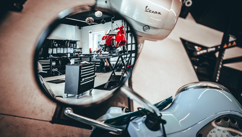 Mobili e armadietti da officina in 3D Beta visibili in un garage riflesso nello specchio di uno scooter