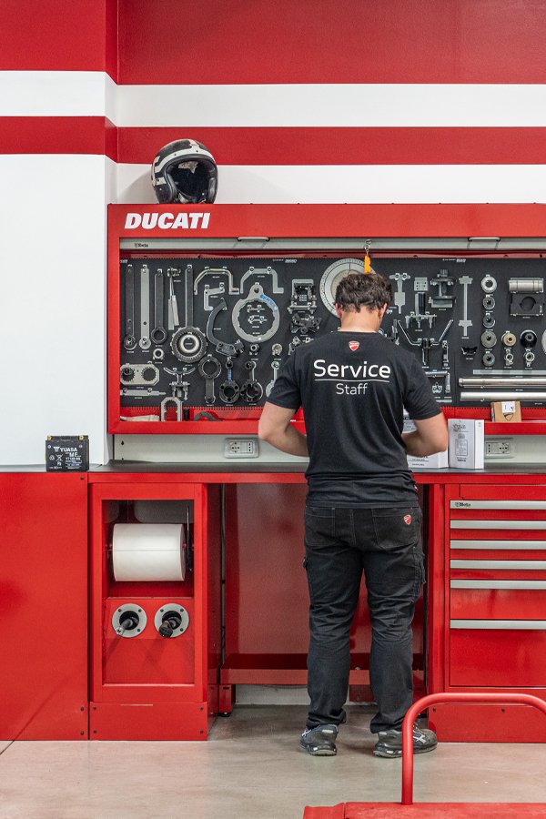 Mobili e soluzioni per l'officina con un meccanico dell'Officina moto Ducati Alessandria accanto alla parete degli attrezzi